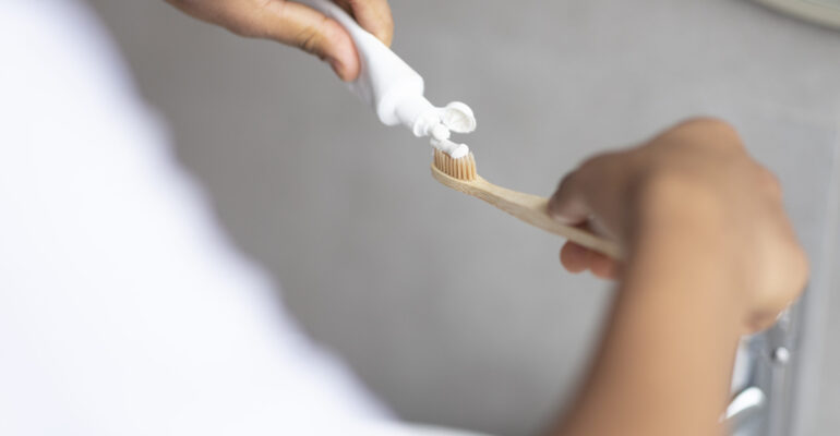 Daily dental care. Male hands pouring toothpaste on toothbrush, enjoying dental hygiene, closeup