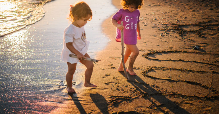 little sisters drawing on sand